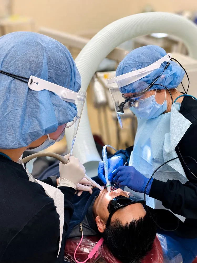 Clinical team in full personal protective equipment performing a precision dental procedure