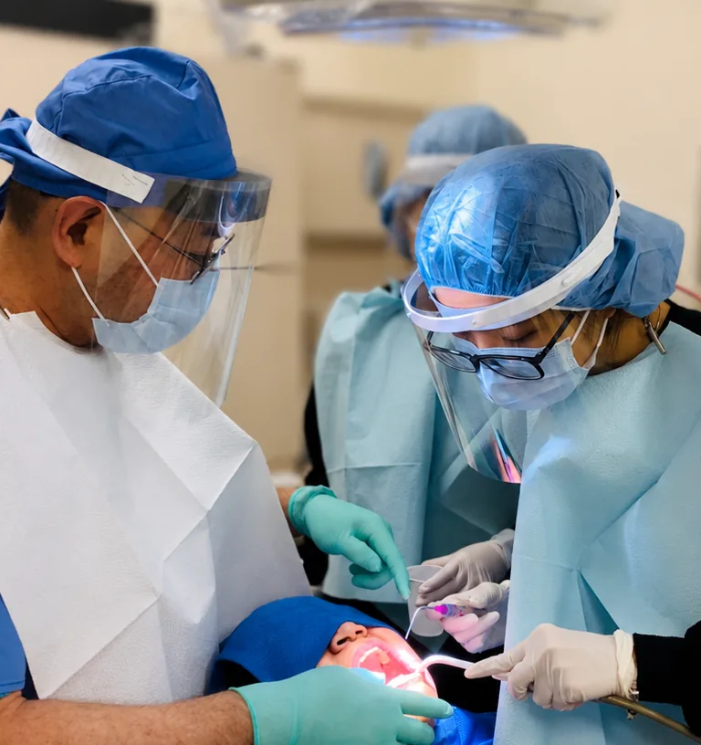 Dr. Minh Nguyen and a SoftDental assistant in full PPE performing a procedure on a patient